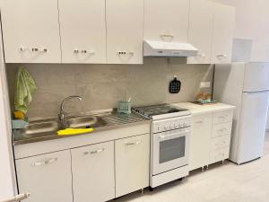 eine Küche mit weißen Schränken, einer Spüle und einem Kühlschrank in der Unterkunft Casa Gaia - Proppro SRL - Vicino Milazzo in San Biagio