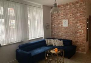 ein Wohnzimmer mit einem blauen Sofa und einer Ziegelwand in der Unterkunft Apartament Szum Fal przy Plaży Międzyzdroje in Misdroy