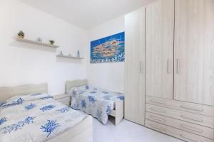 a white bedroom with two beds and a cabinet at Casa Elisabetta - Goelba in Portoferraio