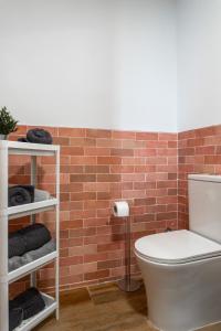 a bathroom with a toilet and a brick wall at Estudio completo a estrenar en Triana in Seville