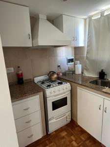 a white kitchen with a stove and a sink at Departamento calle 32 in Balcarce