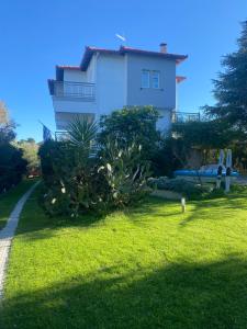 a white house with plants in front of a yard at FERRUM house in Hanioti