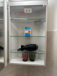 a cupboard with a flashlight and two bowls in it at Comodo appartamento nel cuore dell'Engadina in Celerina