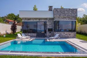 a swimming pool with two chairs and a house at SAPANCA JOWA in Sapanca