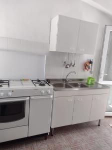 Una cocina blanca con estufa y fregadero. en Gardenia House, en Orosei