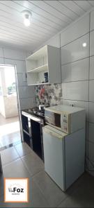 Una cocina blanca con estufa y refrigerador. en Vila Foz HOSTEL AP6 Apartamento completo de casal com garagem fechada e lavanderia, Temos Uber e guia turístico para indicar, Nosso apartamento é o melhor custo benefício de Foz do Iguaçu, en Foz do Iguaçu