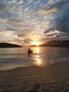 una persona en un barco en el agua al atardecer en kitnet da Ana, en Arraial do Cabo