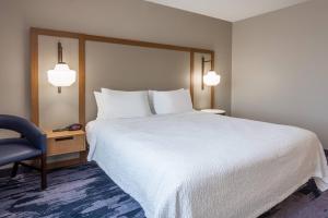 a hotel room with a large bed and a blue chair at Fairfield Inn & Suites Indianapolis Northwest in Indianapolis