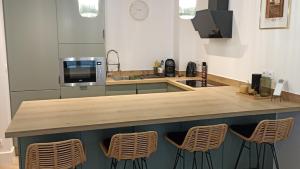 a kitchen with a counter with a microwave and chairs at Appartement Vaux le Vicomte in Boissettes