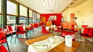 a dining room with red chairs and tables in a restaurant at Hotel Central in Nuremberg