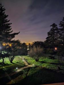 a field at night with trees and a path at Le Cocon à Bulles in Charly