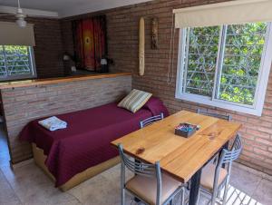 Habitación con cama y mesa de madera con sillas. en El Cabure Complejo, en Villa Carlos Paz