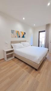 a white bedroom with a large bed and a wooden floor at Casa al Duomo in Nicosia