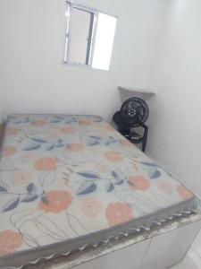 a bed in a room with a floral bedsheet at Casa de temporada na Baía da Traição in Baía da Traição