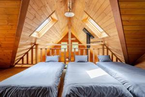two beds in a room with wooden walls and windows at 白馬のスキー場まで４分お洒落なログハウス『白馬 MAMMOTH HOUSE』 in Hakuba