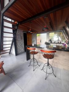 a kitchen with two bar stools and a counter at Chalé Cabana Morro dos Ventos in Chapada dos Guimarães