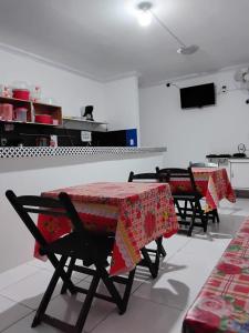two tables in a kitchen with red table cloths on them at Pousada Dipajuçara in Maceió