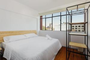 a bedroom with a white bed and a large window at Edificio Aurora in Mexico City