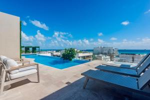 a patio with a view of a swimming pool and the ocean at Playa Azul Studio - Coco Beach I in Playa del Carmen