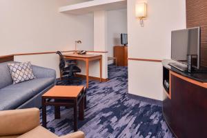 a living room with a couch and a desk with a tv at Fairfield Inn & Suites Raleigh-Durham Airport/Brier Creek in Durham