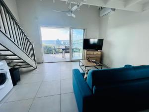 a living room with a blue couch and a television at La pinta SXM in Oyster Pond