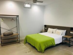a bedroom with a bed with a green blanket on it at La Majorera in Villaverde