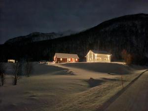 特罗姆瑟Malangen Lodge的雪覆盖的田地中间的房子