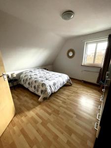 a bedroom with a bed and a wooden floor at Appartement Betschdorf Cité des potiers in Oberbetschdorf