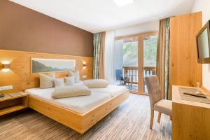 una camera con letto, scrivania e finestra di Hotel Mathiesn a Obergurgl