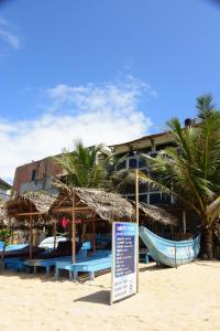 a hotel on the beach with a sign in the sand at Happy Tuna Beach Apartment in Hikkaduwa