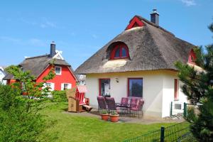 een huis met een rieten dak en stoelen in een tuin bij Seemöwe in Glowe
