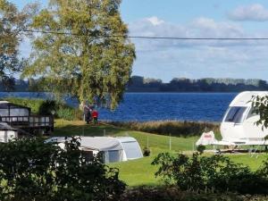 a white tent on the grass next to a lake at Ostseewellen II Haushälfte in Stahlbrode