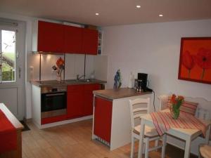 une cuisine avec des armoires rouges et une table et des chaises dans l'établissement Nordlicht, à Hamburgerdeich 19 autres photos