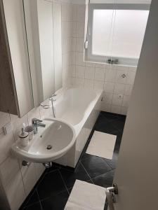 a bathroom with a white tub and a sink at Gemütliche 3 Zimmer Wohnung mit Balkon und Fernblick in Nürnberg