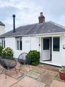 a white house with two chairs in front of it at The Retreat, self-contained cosy Anex, M6 A75 Gretna Green in Rigg