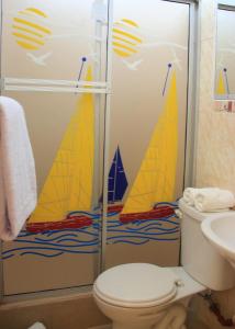 a bathroom with a toilet and a shower with sailboats on it at Hostal El Pinzón in Puerto Ayora