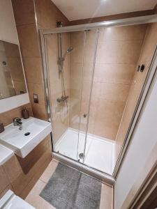 a shower with a glass door next to a sink at Modern and Spacious 2 bedroom Flat in Streatham in London +27 photos