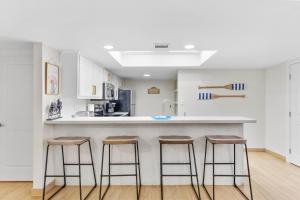 a kitchen with three bar stools at a counter at Ground Floor Beachfront 2 Steps From Amenities IV in South Padre Island