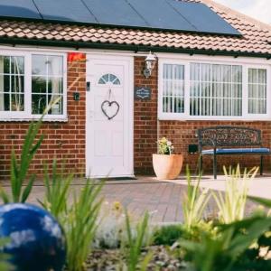 a brick house with a white door with a heart on it at New Inn Lodge In Scarning Near Dereham Norfolk England in East Dereham