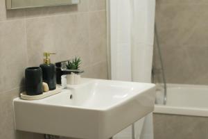 ein weißes Waschbecken in einem Badezimmer mit Dusche in der Unterkunft LZR Apartments in Braşov + 14 Fotos