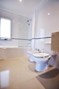 a white bathroom with a toilet and a sink at La Mirage in Villa Gesell