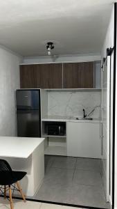 a kitchen with a black refrigerator and white cabinets at Flat aconchegante perto da praia in São Vicente