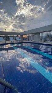 a swimming pool with chairs and clouds in the sky at Flat aconchegante perto da praia in São Vicente
