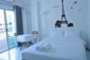 um quarto com uma cama branca e uma torre Eiffel. em V Suvarnabhumi วี สุวรรณภูมิ em Bang Phli