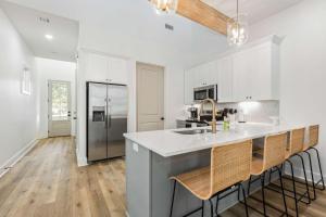 Una cocina con gabinetes blancos y una isla de cocina con taburetes de bar. en New cottage near Sports Complex with King Beds, en Youngsville