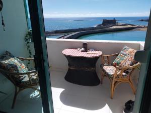 a balcony with two chairs and a table and a swimming pool at Beautiful room with magic ocean view in Arrecife