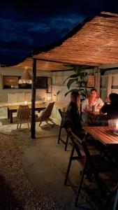 un grupo de personas sentadas en una mesa de picnic por la noche en El Bonito Hostel, en Cabo Polonio