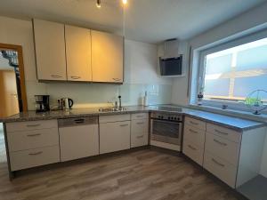 eine Küche mit weißen Schränken und einer Spüle und einem Fenster in der Unterkunft Ferienwohnung Steverding in Bocholt