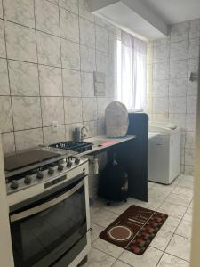 a white kitchen with a stove and a sink at Cantinho aos pés do Ibituruna in Governador Valadares