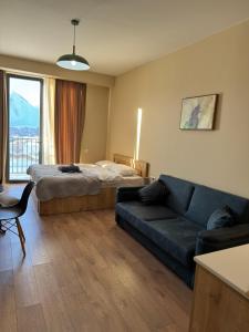 ein Wohnzimmer mit einem Bett und einer Couch in der Unterkunft New Gudauri, Alpic - Ski Resort at Your Doorstep - Stylish & Comfy Ski Apartment with ski-depot and Stunning Mountain Views in Gudauri